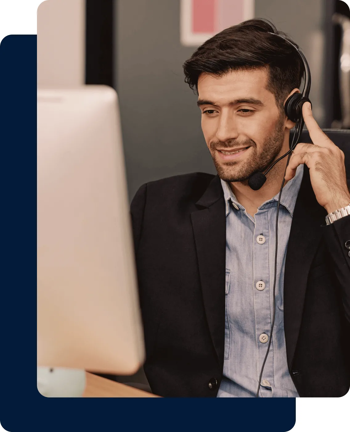 A male agent on a phone call in front of a desktop