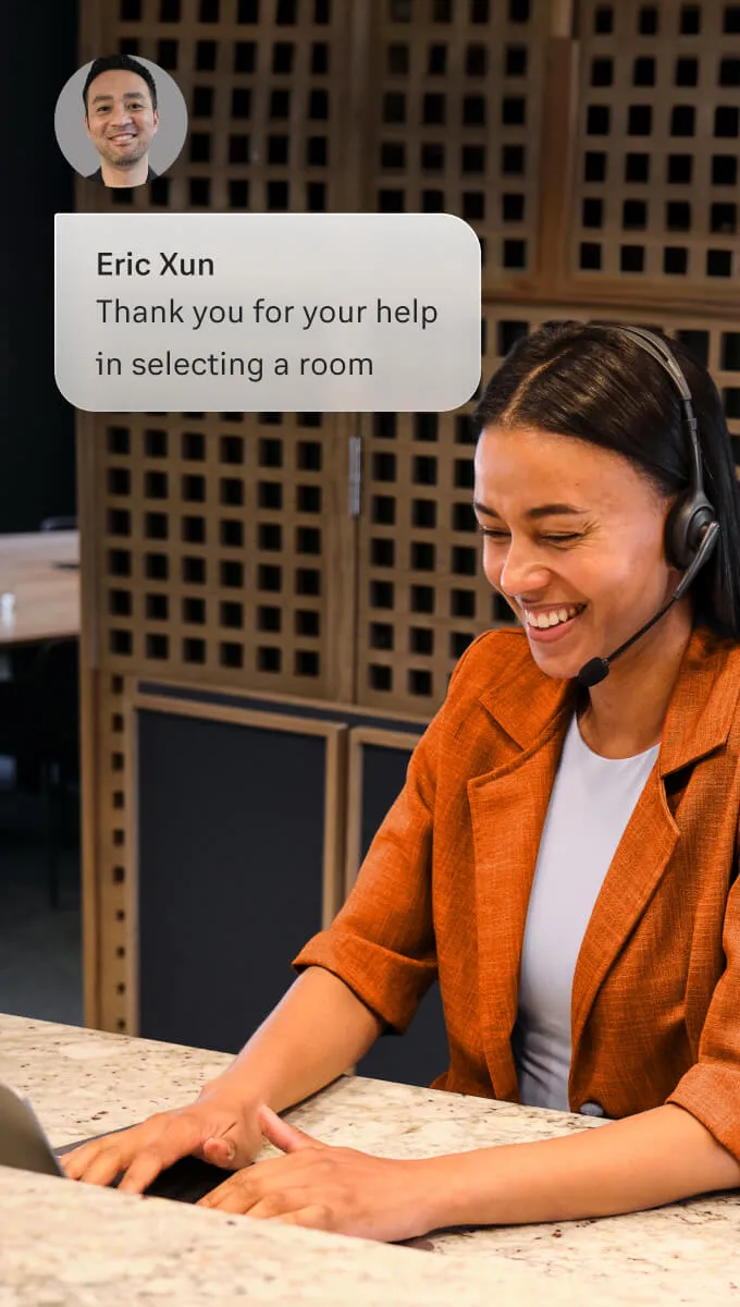 A female concierge speaks to a guest via a headset and laptop