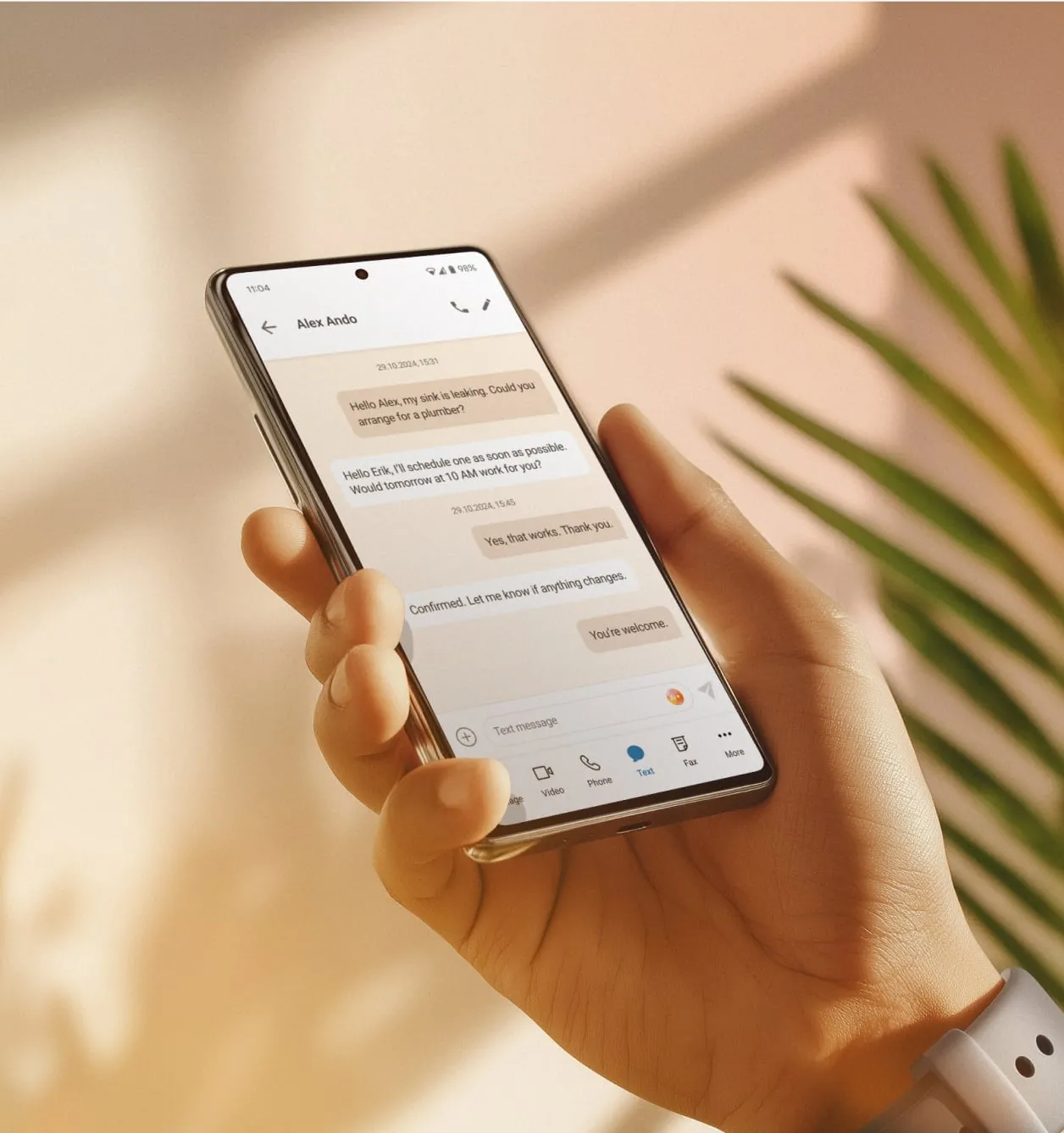 A hand is holding a phone showing a text exchange between a landlord and a tenant.