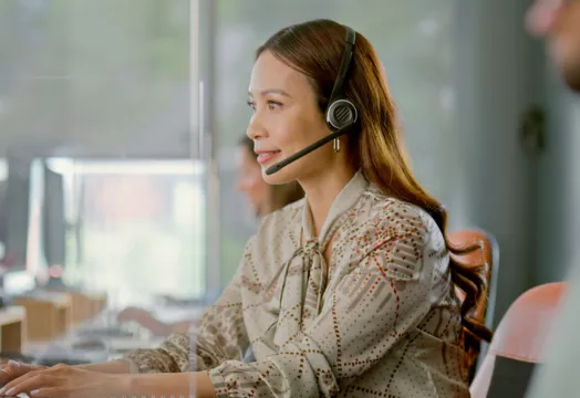 A woman wearing a headset speaks to a customer