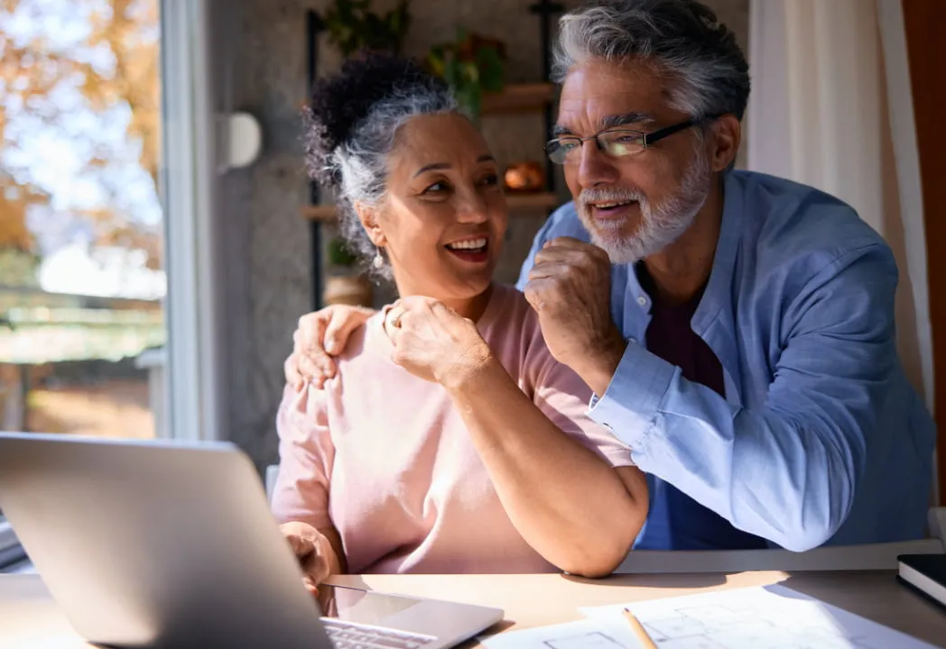  A senior couple sits together, engaged in using a laptop, sharing a moment of connection and technology.